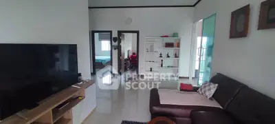 Spacious living room with modern decor and large TV, leading to a cozy bedroom.