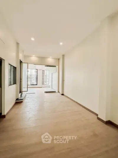 Spacious empty room with large windows and wooden flooring, perfect for customization.