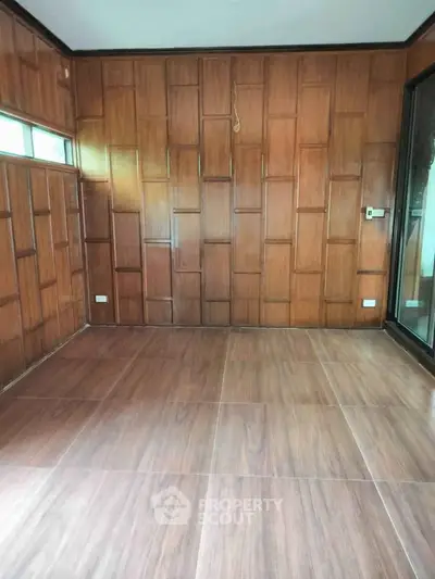Spacious room with elegant wood paneling and large windows, perfect for a cozy living space.