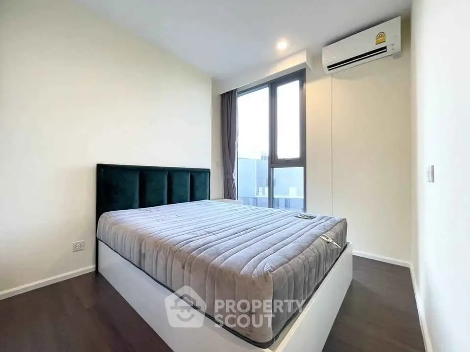 Modern bedroom with large window and air conditioning in a stylish apartment.