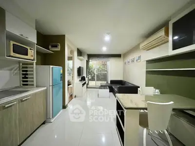 Modern open-layout living room with kitchen, featuring sleek furniture and bright lighting.