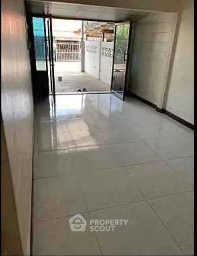 Spacious tiled room with sliding glass doors leading to outdoor area, perfect for versatile use.