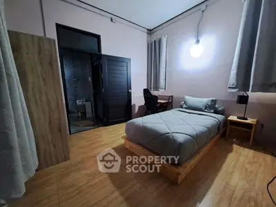 Cozy bedroom with modern decor and wooden flooring, featuring a comfortable bed and study area.