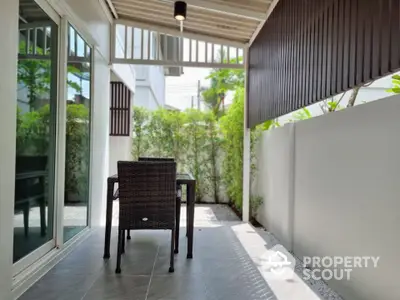 Charming patio with modern outdoor furniture and lush greenery for relaxing ambiance.