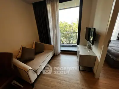 Cozy living room with balcony view, featuring a modern sofa and sleek TV stand.
