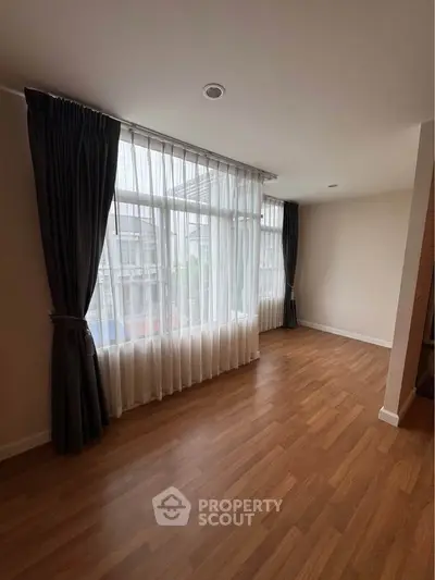 Spacious empty room with large windows and wooden flooring, perfect for customization.