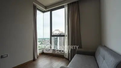 Modern apartment corner with large windows and city view, featuring a cozy gray sofa.