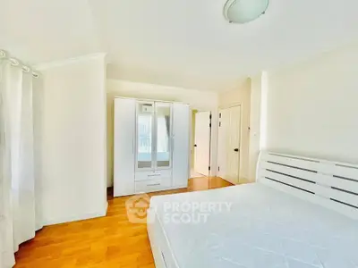 Bright and spacious bedroom with wooden floors and modern white furniture.