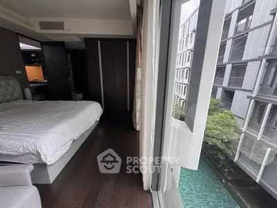 Modern bedroom with large window offering poolside view in luxury apartment.