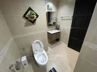 Modern bathroom with elegant fixtures and neutral tiles, featuring a sleek vanity and contemporary toilet design.