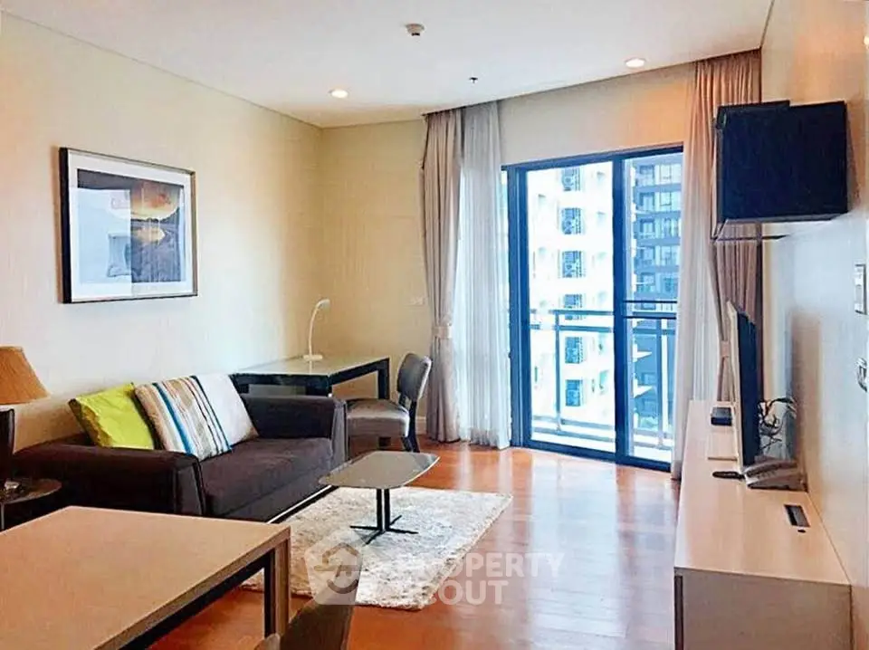 Modern living room with balcony view in a high-rise apartment, featuring stylish furniture and ample natural light.