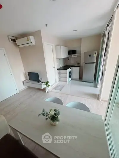 Modern open-layout living room with kitchen, featuring washing machine and fridge, ideal for urban living.