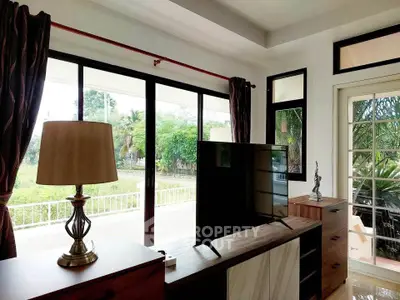 Spacious living room with large windows and garden view, perfect for relaxation.