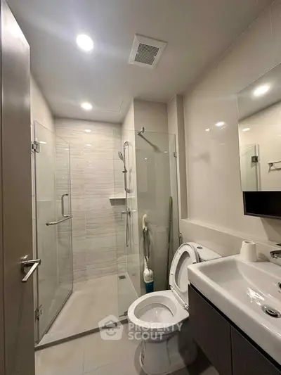 Modern bathroom with glass shower and sleek fixtures in contemporary home.