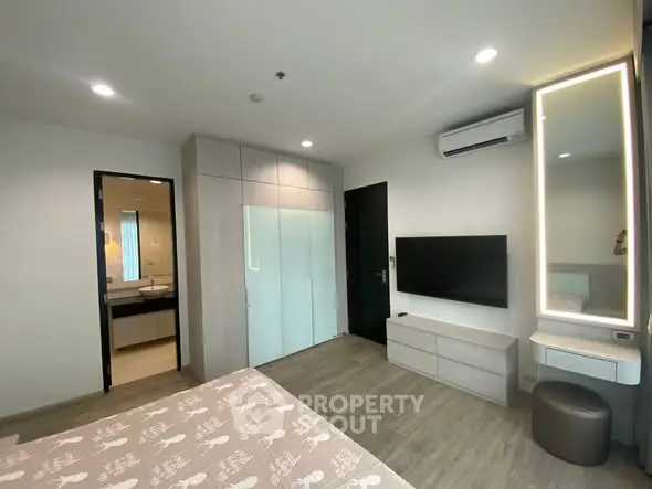 Modern bedroom with stylish decor and ensuite bathroom in contemporary apartment.