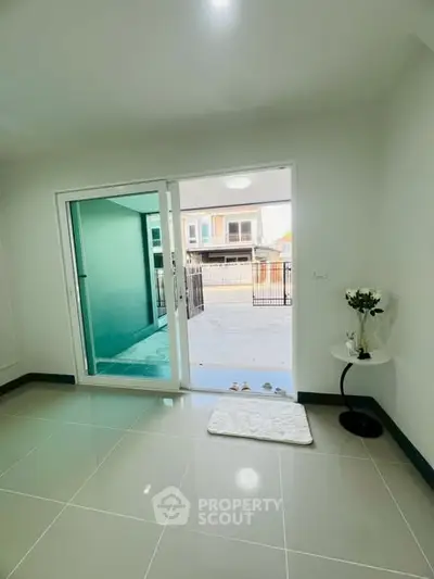 Modern interior with sliding glass doors leading to a patio, featuring sleek tile flooring and minimalist decor.
