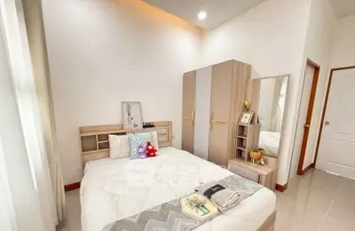 Cozy bedroom with modern decor and ample natural light, featuring a stylish wardrobe and elegant bedding.