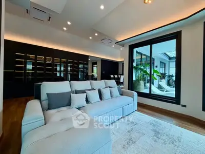 Luxurious living room with modern sofa and large window overlooking a stylish patio.