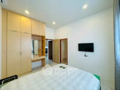 Modern bedroom with built-in wardrobe and wall-mounted TV in a bright apartment.