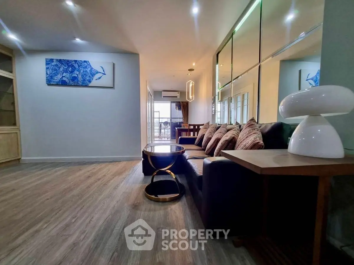 Spacious living room with modern decor and elegant lighting, featuring a cozy sofa and stylish coffee table.
