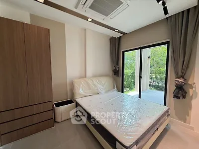Modern bedroom with large window and garden view, featuring a comfortable bed and stylish wardrobe.