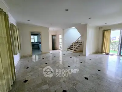 Spacious open-plan living room with marble flooring and natural light.