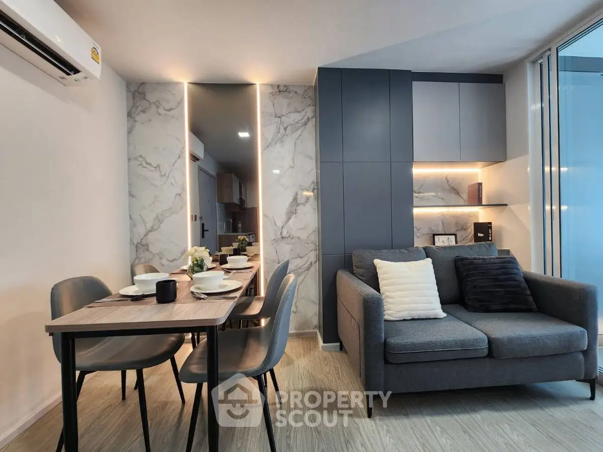 Modern living room with stylish dining area and cozy sofa, featuring elegant lighting and marble accents.
