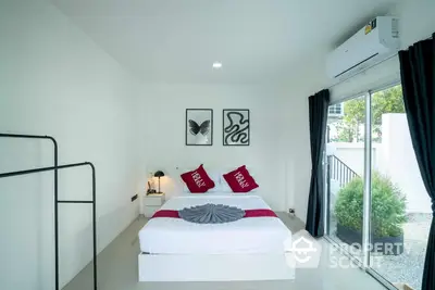 Modern minimalist bedroom with white walls, a comfortable double bed with red accent pillows, and sliding glass doors leading to a private outdoor area.