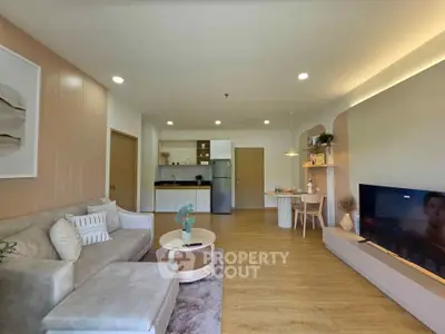 Modern living room with open kitchen, stylish decor, and cozy seating area.