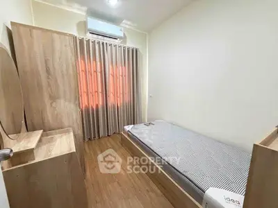 Cozy bedroom with single bed, wooden furniture, and air conditioning.