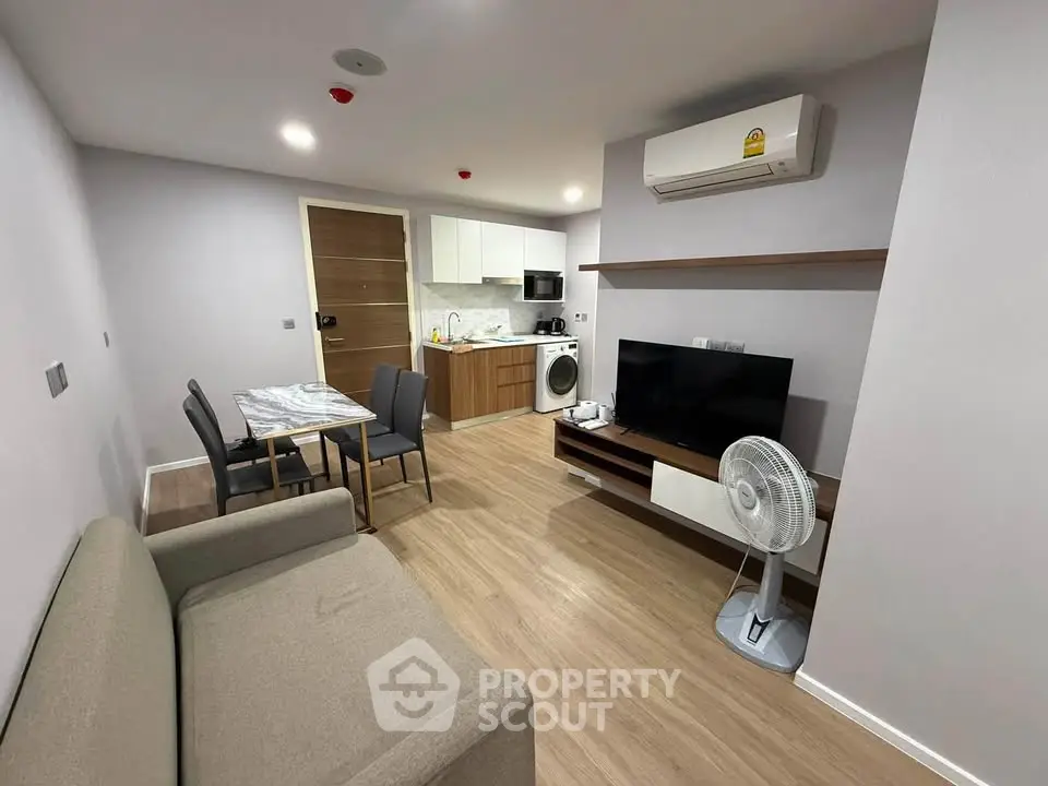 Modern living room with open kitchen, featuring sleek furniture and appliances, ideal for urban living.
