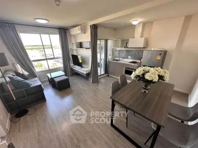 Modern open-plan living room with kitchen, featuring stylish furniture and large window for natural light.