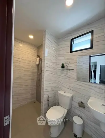 Modern bathroom with sleek design, featuring a shower, toilet, and stylish tile work.