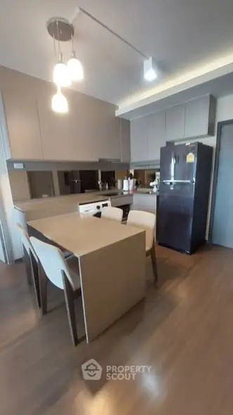 Modern kitchen with sleek cabinetry, dining table, and appliances in a stylish apartment.