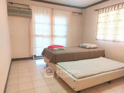 Cozy bedroom with natural light and simple decor, featuring a comfortable bed and air conditioning.