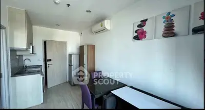 Modern kitchen with dining area, featuring sleek cabinets and air conditioning.