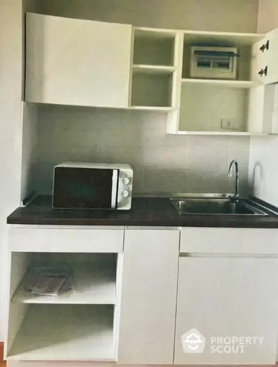 Modern compact kitchen with white cabinetry and microwave