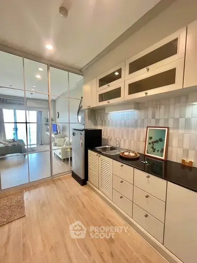 Modern kitchen with sleek cabinets and open layout leading to spacious living room.