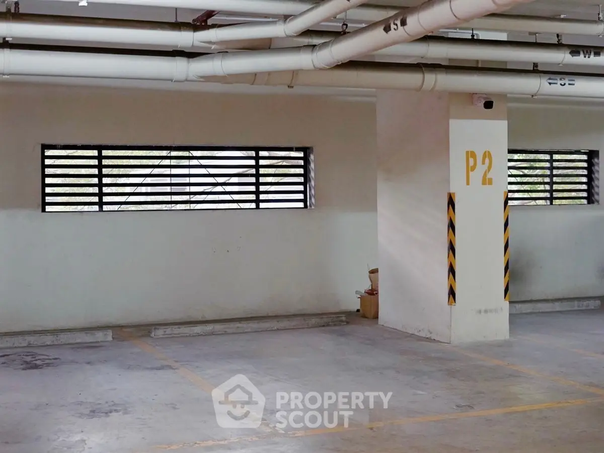 Spacious indoor parking area with marked spaces and security camera, ideal for secure vehicle storage.