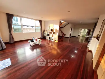 Spacious living room with wooden flooring and ample natural light, perfect for family gatherings.
