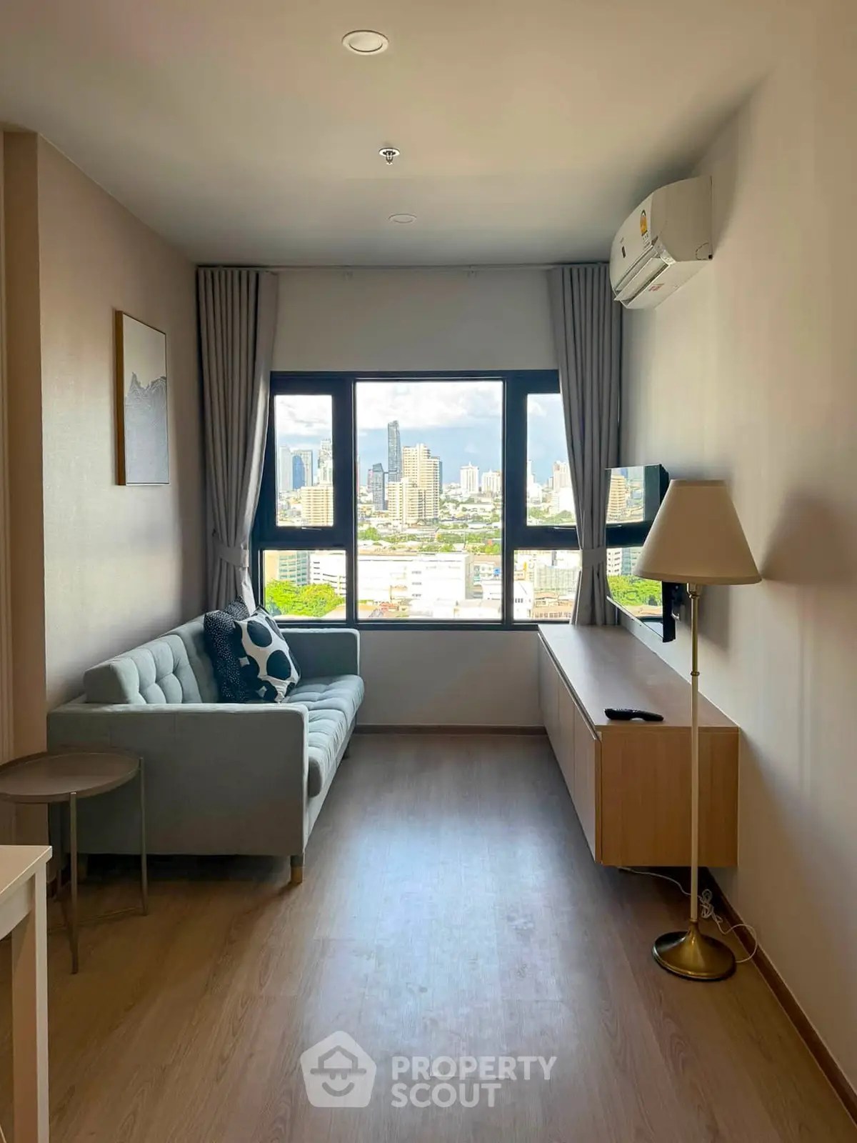 Modern living room with city view, featuring a cozy sofa and sleek furniture, perfect for urban living.