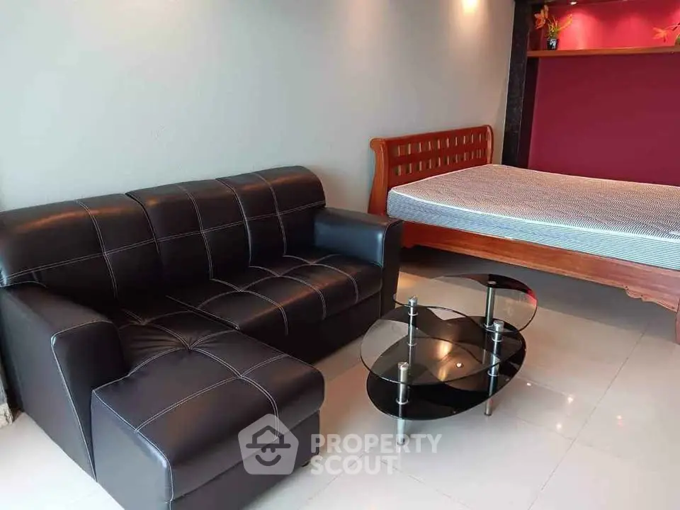 Modern studio apartment with sleek black sofa and stylish glass coffee table