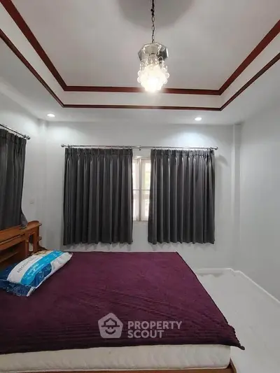 Spacious bedroom with elegant ceiling design and large windows for natural light.
