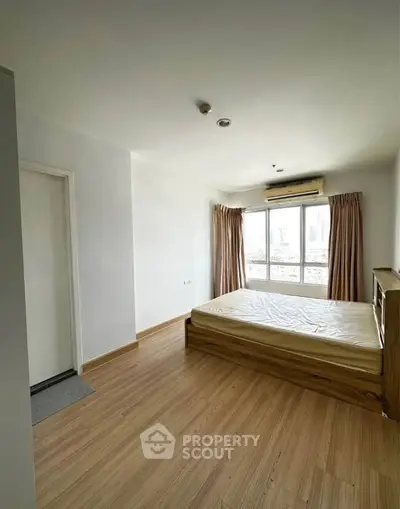 Bright bedroom with wooden flooring and large window for natural light