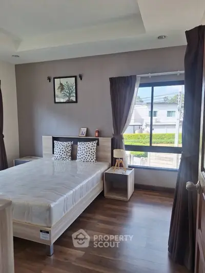 Bright and cozy bedroom with modern decor and large window view.