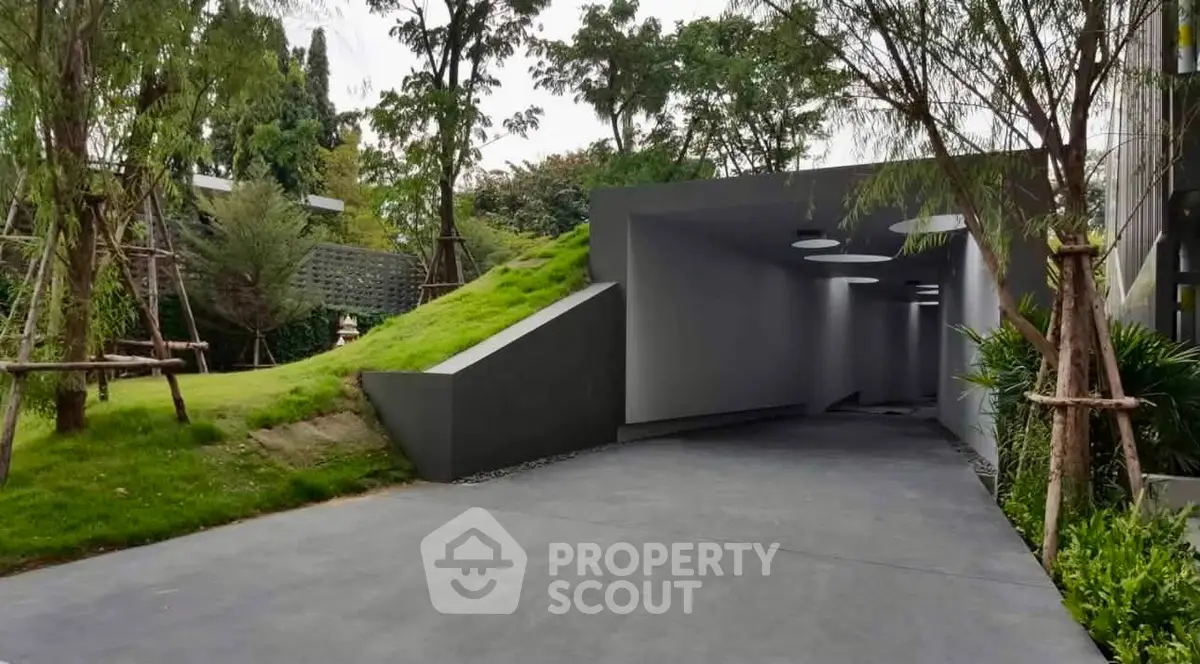 Modern architectural entrance with sleek design and lush greenery, perfect for luxury real estate appeal.