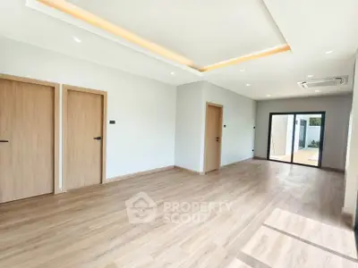 Spacious modern living room with wooden flooring and ample natural light.