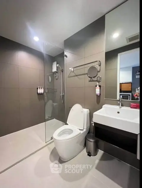 Modern bathroom with glass shower and sleek fixtures in contemporary apartment.