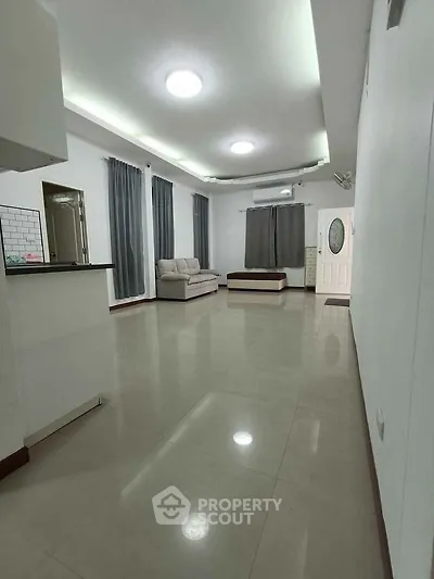 Spacious living room with modern lighting and sleek tile flooring, perfect for relaxation.
