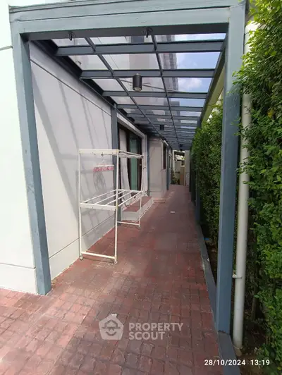 Modern exterior walkway with glass canopy and brick path in residential property